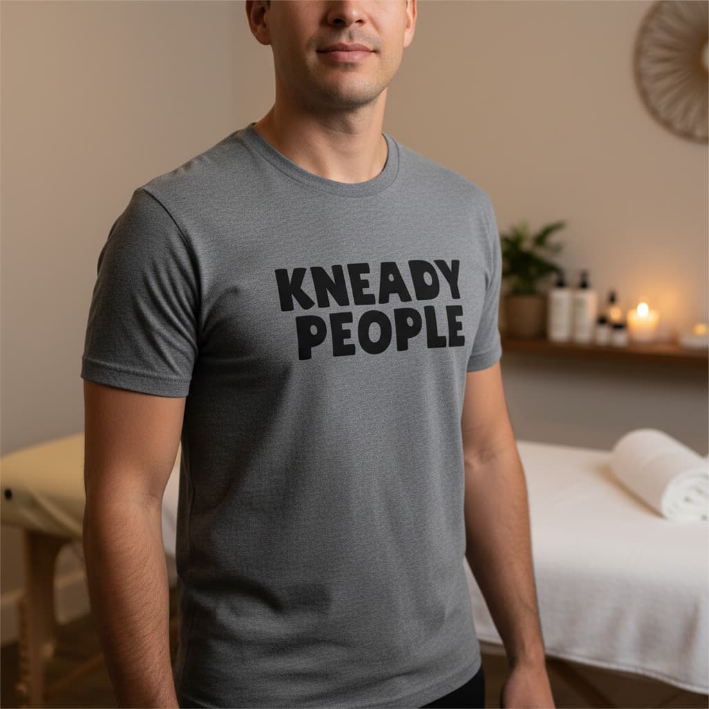 Massage therapist wearing a heather grey Kneady People t-shirt in a treatment room